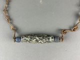 a close up of a gold chain with a blue bead on it
