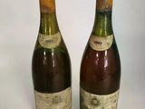 two bottles of wine sitting next to each other on a white surface