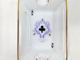 a white and gold ashtray with a playing card on it