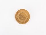 a gold coin on a white surface with a white background