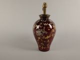 un vase rouge et doré surmonté d'une lampe