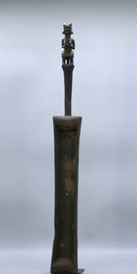 une statue représentant un homme debout au sommet d'un poteau