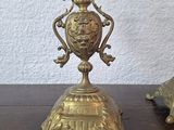 pair of antique brass candlesticks on a wooden table with a white wall in the background