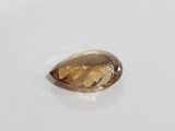 a close up of a faceted golden quartz stone on a white surface