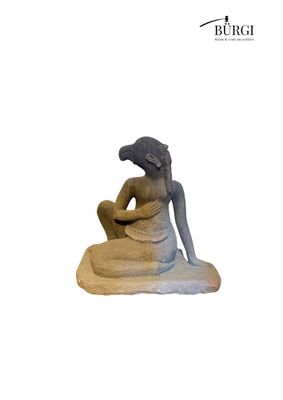 a statue of a woman sitting on a rock