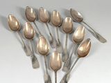 Plusieurs cuillères sont disposées en cercle sur une surface blanche.