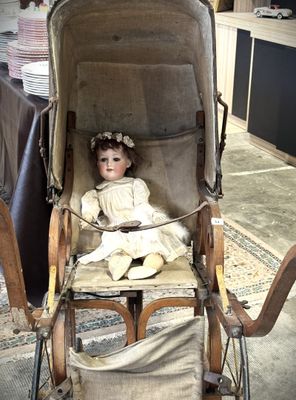 une poupée assise dans une poussette, dans une pièce