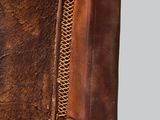 a close up of a chair with a brown leather seat