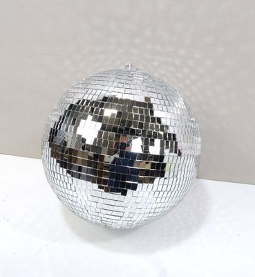 une boule à facettes posée sur une surface blanche, avec une personne en train de prendre une photo
