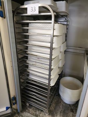many trays of food on a metal rack in a kitchen