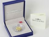 une pièce d'or dans une boîte bleue accompagnée d'une carte