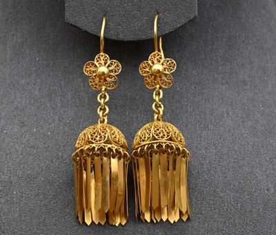 a pair of gold toned earrings on a mannequin mannequin