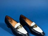 a pair of black and white shoes with a gold chain