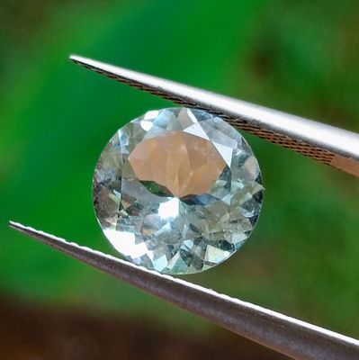 quelqu'un tient une pince dans laquelle est sertie un diamant bleu