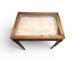 an old wooden table with a glass top sitting on a white surface