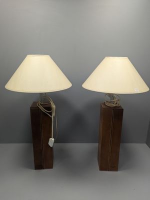 pair of wooden table lamps with white shades on them