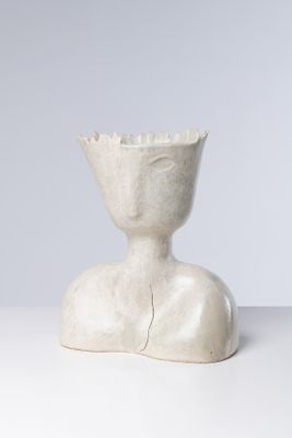 une sculpture blanche représentant une personne assise sur une table