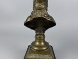 a bronze bust of a man with a hat on a stand