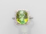 gros plan d'une bague avec une pierre verte entourée de diamants blancs