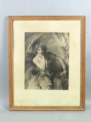 an old photo of a woman sitting on a horse with a dog