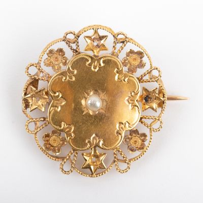 une image d'une broche en or avec une perle au centre
