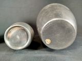 two metal containers sitting next to each other on a table
