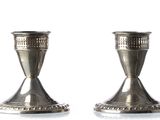 two silver candlesticks on a white surface