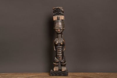 une statue en bois représentant un homme debout sur une table en bois