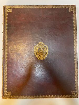 un vieux livre en cuir brun portant un emblème doré