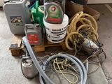 un tas de bric-à-brac par terre, à côté de quelques bidons et tuyaux
