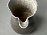 a small silver vase with a handle on a table