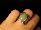 someone is holding a ring with a green stone on it