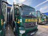 two green trucks parked next to each other in a parking lot