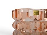 a pink glass vase with a gold label on it