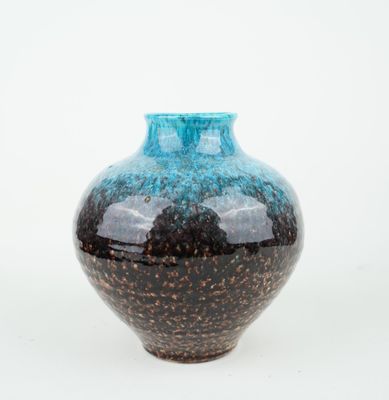 a blue and black vase sitting on a white surface