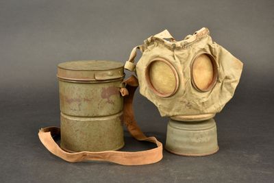 an old gas mask and a canister on a gray background