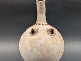 a white vase with a face on it on a gray surface