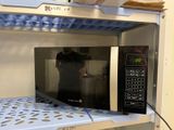 someone is taking a picture of a microwave on a shelf