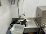 a kitchen with a sink and a trash can in it