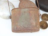 a small metal bag sitting on a table next to some rocks