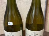 two bottles of wine sitting on top of a table next to each other
