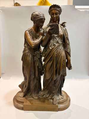 a bronze statue of two women standing next to each other