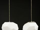 une paire de suspensions en verre blanc et métal sur fond noir