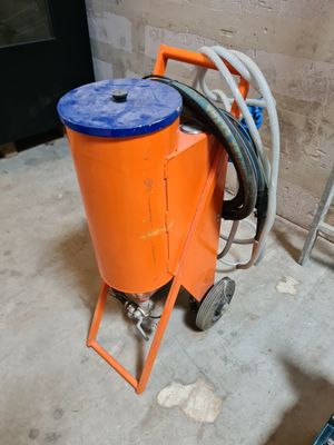 une machine orange sur laquelle est posé un seau bleu, dans une pièce