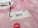 a label on a pink sweater with lipstick prints on it