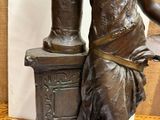 a bronze statue of a woman holding a book
