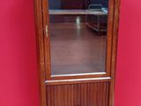 une vieille armoire en bois surmontée d'un miroir, placée devant un mur rouge
