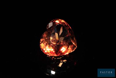 a close up of an orange diamond on a black surface
