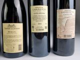 three bottles of red wine are lined up on a table