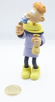 figurine of a man with a toothbrush in his mouth next to a coin